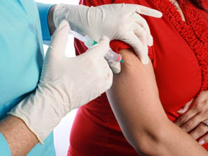 Les mans d'un professional sanitari amb guants administren una vacuna a una persona adulta