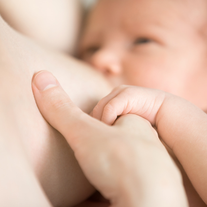 Una mare alleta el seu nadó mentre s'agafen de la mà