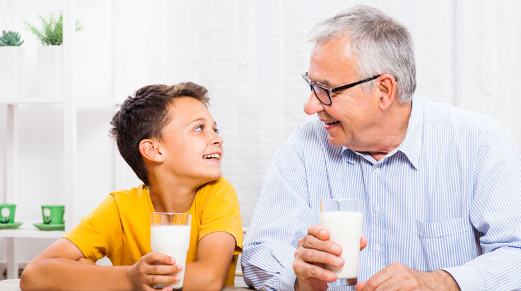 Un infant i el seu avui beuen un got de llet cadascun asseguts davant d'una taula