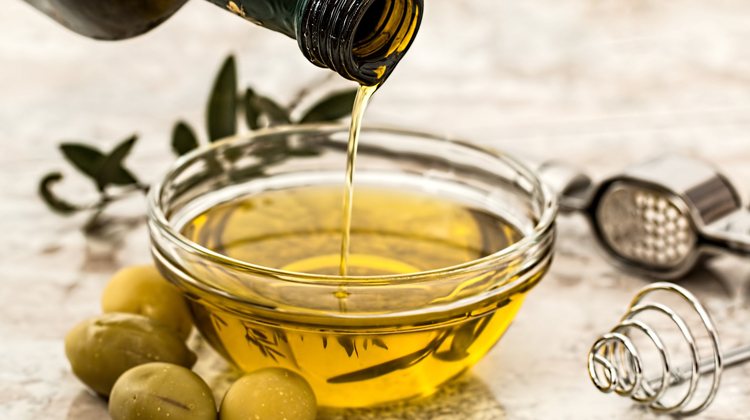 Un petit bol s'omple d'oli d'oliva damunt d'una taula