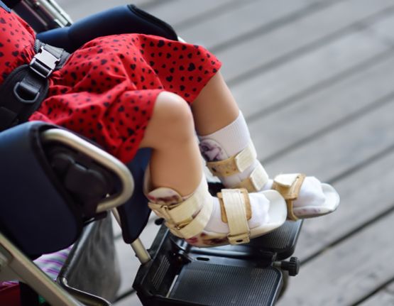 Una nena amb paràlisi cerebral asseguda en una cadira de rodes