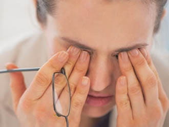 Una noia es frega els ulls amb les mans mentre subjecta les ulleres amb una mà