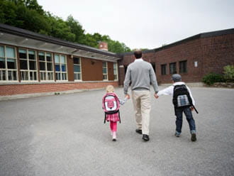 Un pare arriba a la porta de l'escola amb els seus dos fills
