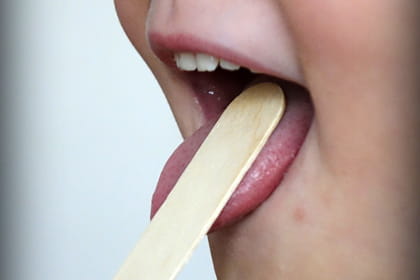 Pla detall de la boca d'un infant mentre n'examinen la gola