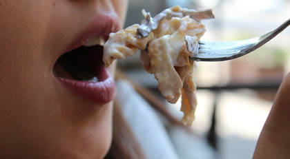 La boca d'una noia a punt de menjar un aliment amb una forquilla