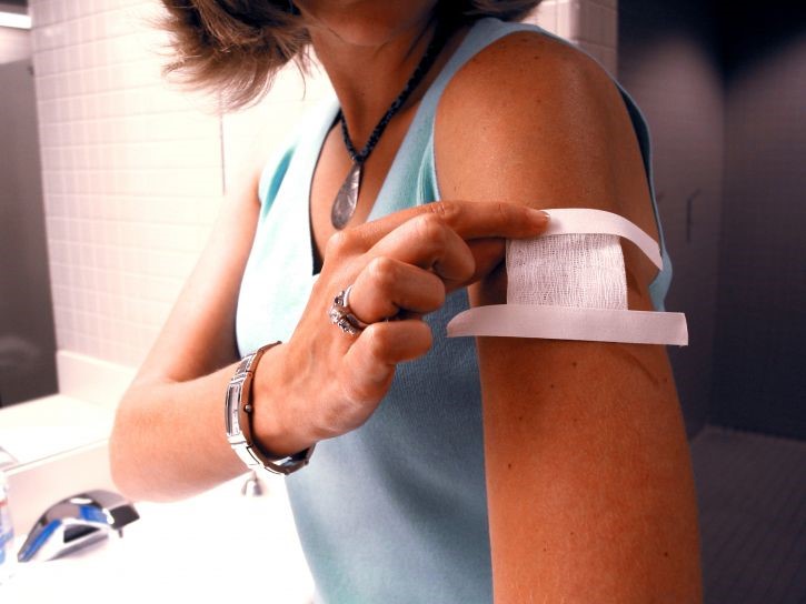 Una dona es cobreix una zona del braç amb un apòsit