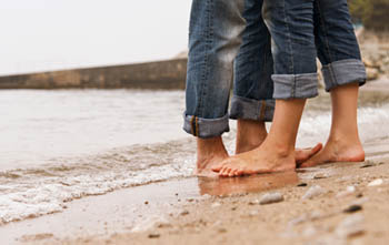 Les cames de dues persones abraçades a la vora del mar.