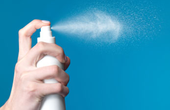 Una mà pressiona el tap d'una ampolla de spray