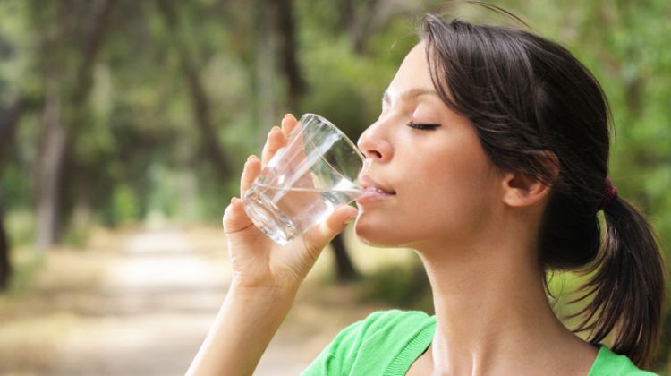 Una noia tria una ampolla d'aigua en lloc d'una llauna de refresc