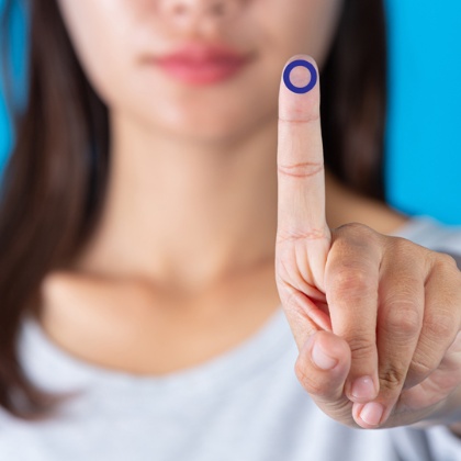Una noia amb el cercle blau, símbol del Dia Mundial de la Diabetis, a la punta del dit índex de la mà esquerra