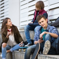 Tres joves xerren asseguts en unes escales del carrer