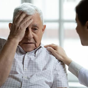 Un home gran es toca la cara en un gest de confusió mentre una metgessa li toca l'espatlla en un gest de comprensió