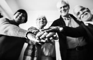 Un grup de persones grans posant les mans de forma col·laborativa i positiva