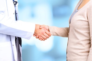 Un professional sanitari i una pacient es donen la mà