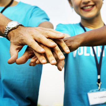 Un grup de voluntaris fa un gest d'equip amb les mans