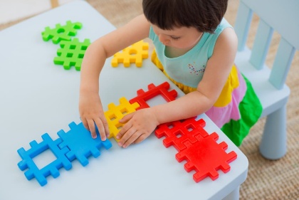 Una nena juga amb peces de colors damunt d'una taula