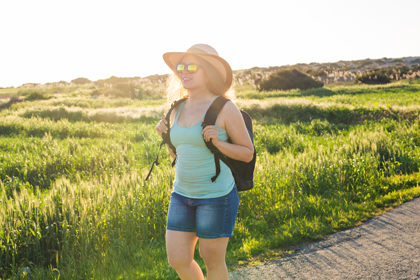Una noia passeja a l'aire lliure amb ulleres de sol i barret