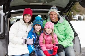 Una família asseguda al maleter del cotxe enmig de la neu