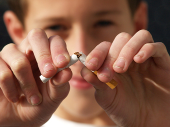 Primer pla d'un infant que trenca una cigarreta amb les mans