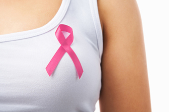 Primer pla del pit d'una noia que porta un llaç rosa com a símbol de lluita contra el càncer de mama