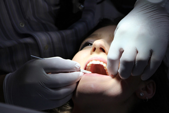 Les mans d'un dentista examinen la boca d'un pacient