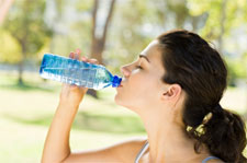Una noia beu aigua d'una ampolla de plàstic a l'aire lliure