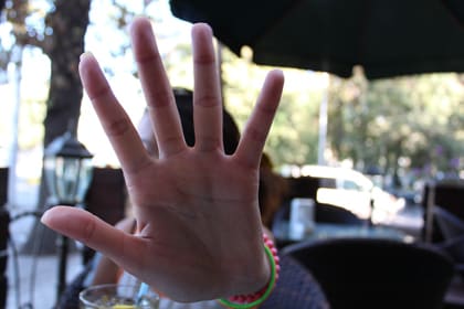 La mà d'una noia en primer pla fa el gest d'aturar-se o rebutjar