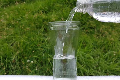 Una ampolla d'aigua mineral omple un got